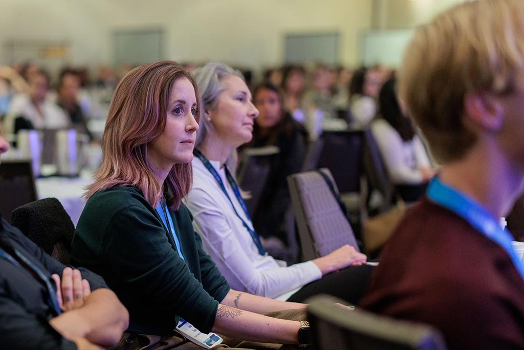 Two women sitting in conference room focused on presentation